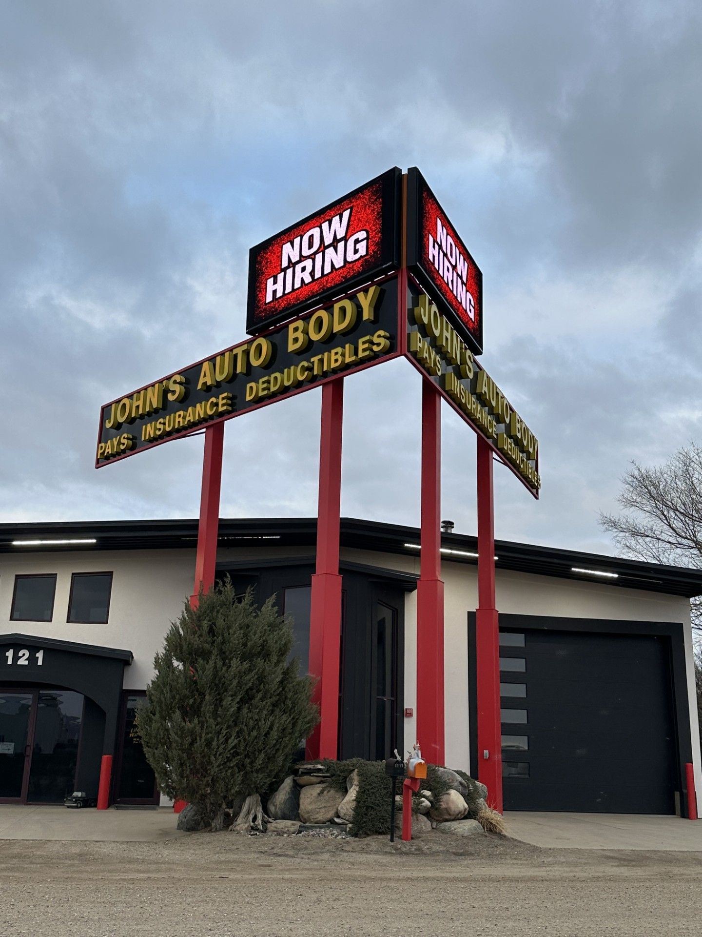 Auto service shop with tall red sign reading “Craw’s Auto Service Center” and “NW Hard Body” under a cloudy sky