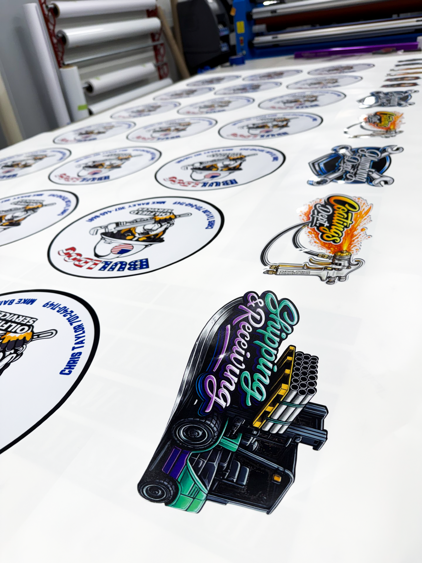 Printed sticker sheets with colorful car and cartoon decals on a roll-fed printer