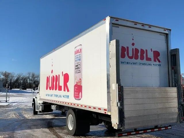 White Bubblr delivery truck in a snowy parking lot under a blue sky