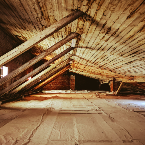 An attic with a wooden ceiling and a brick wall.