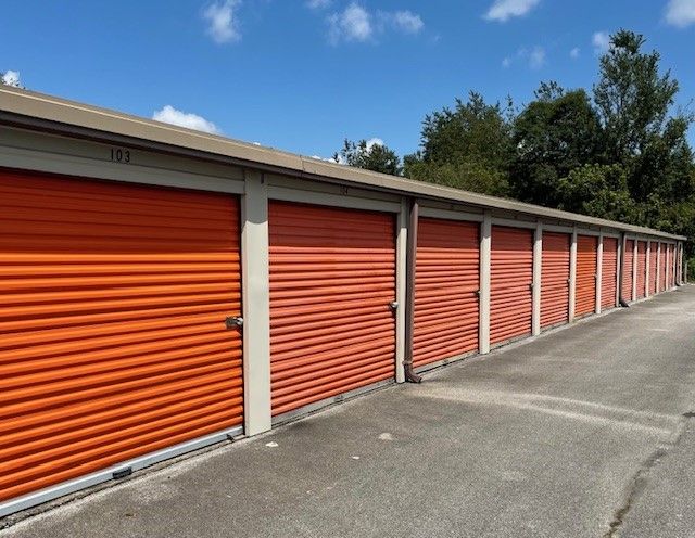 Row of orange storage unit doors under a blue sky.