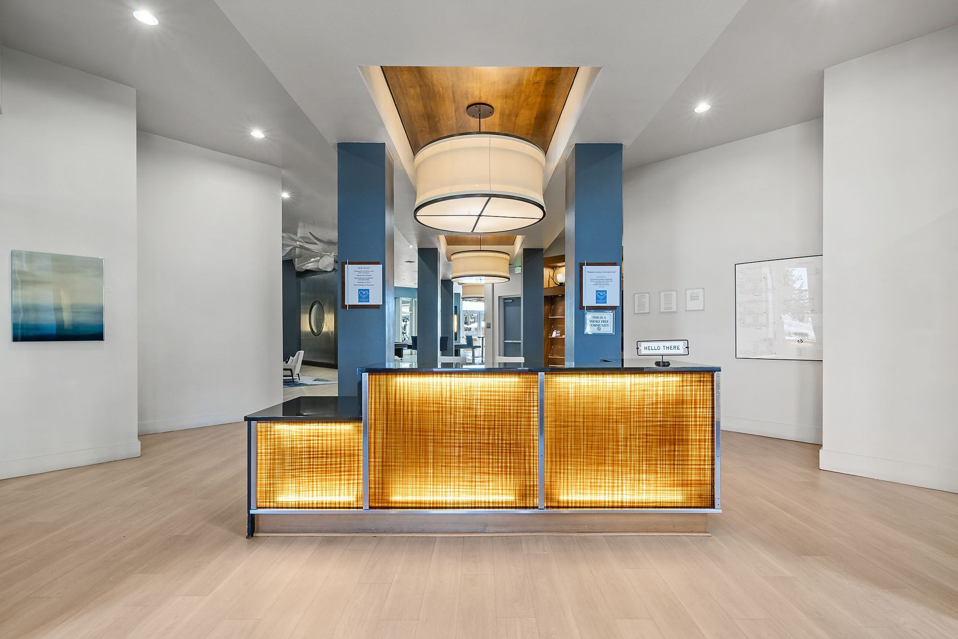 Modern hotel lobby with a glowing front desk, blue columns, and a chandelier centerpiece at The Marq at Ridgegate in Lone Tree, CO.