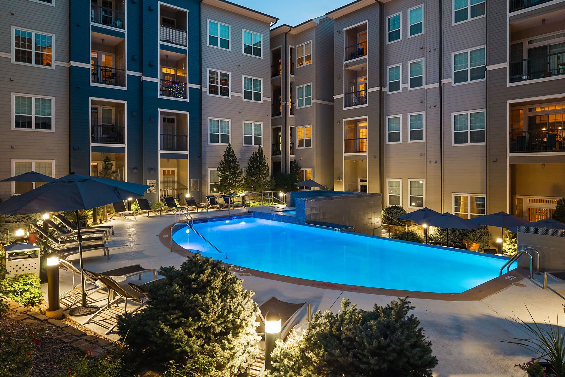 Lit apartment courtyard with a lit blue swimming pool at night at The Marq at Ridgegate in Lone Tree, CO.