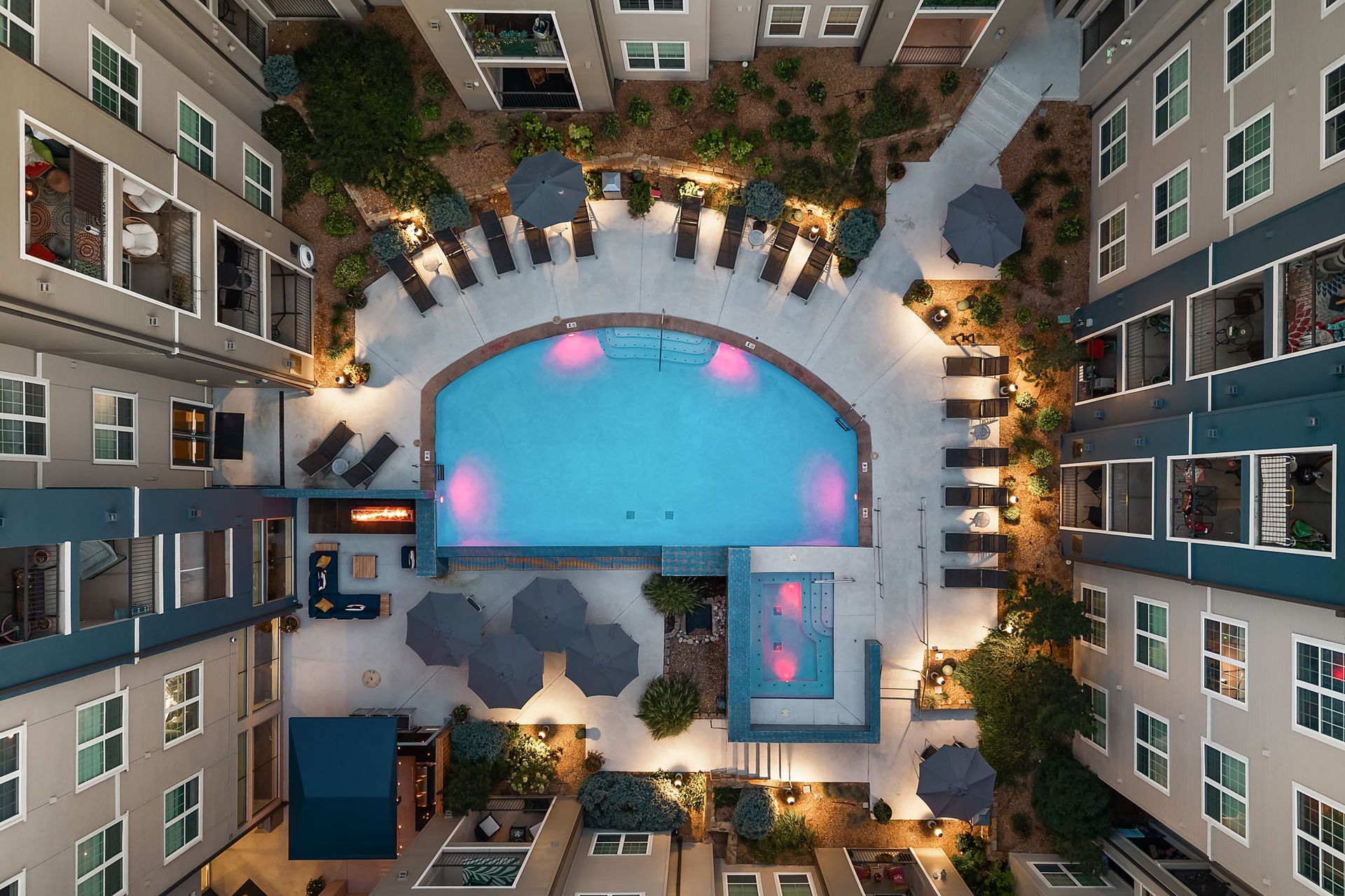 Overhead view of a hotel courtyard with a blue pool, hot tub, and lounge chairs between apartment buildings at The Marq at Ridgegate in Lone Tree, CO.
