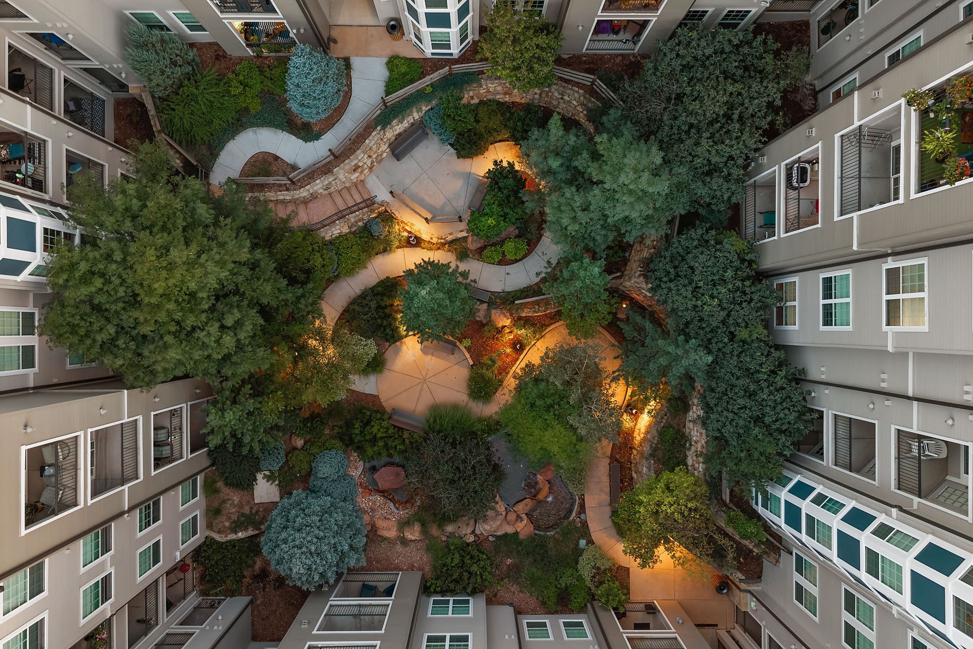 Top-down view of a courtyard garden with winding paths, trees, and warm lights between apartment buildings at The Marq at Ridgegate in Lone Tree, CO.