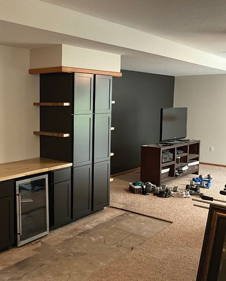 Basement living room with TV, shelves, cabinets, and tools scattered on the floor