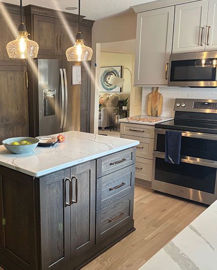 Modern kitchen with dark wood island, white cabinets, stainless appliances, and pendant lights