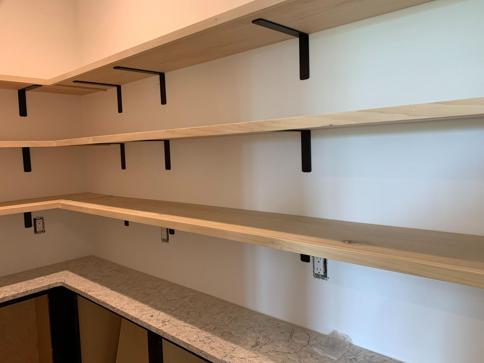 Empty pantry shelves with white walls and a speckled countertop below.