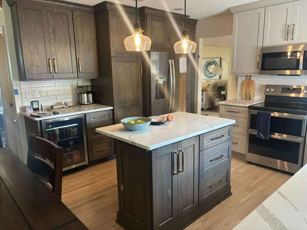 Modern kitchen with dark wood cabinets, stainless appliances, and a central island under pendant lights