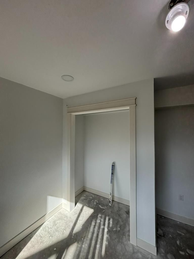 Empty room with gray walls, a closet nook, and sunlight casting window shadows on the floor.
