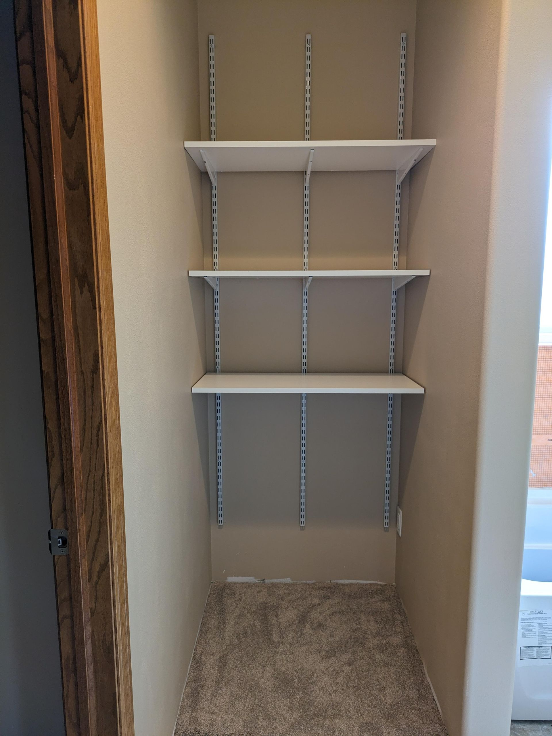 Empty closet with white wire shelves and beige carpeted floor.