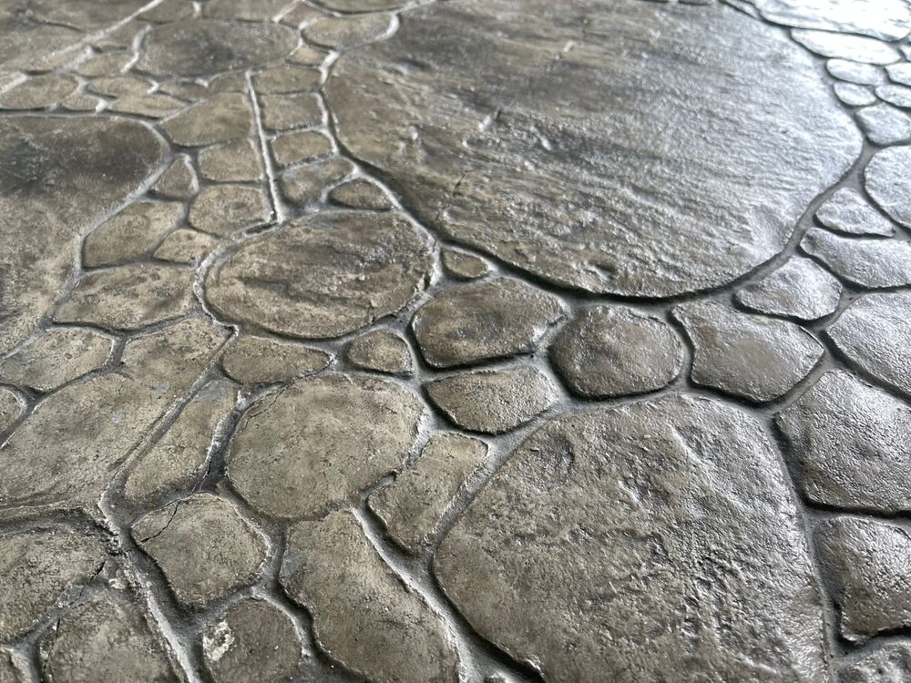 Cracked gray stone pavement with irregular, rounded slabs and rough texture