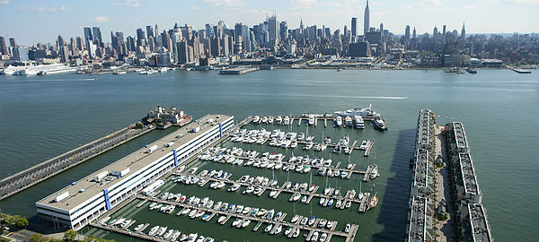 Aerial view of a marina with rows of boats and a city skyline across the water