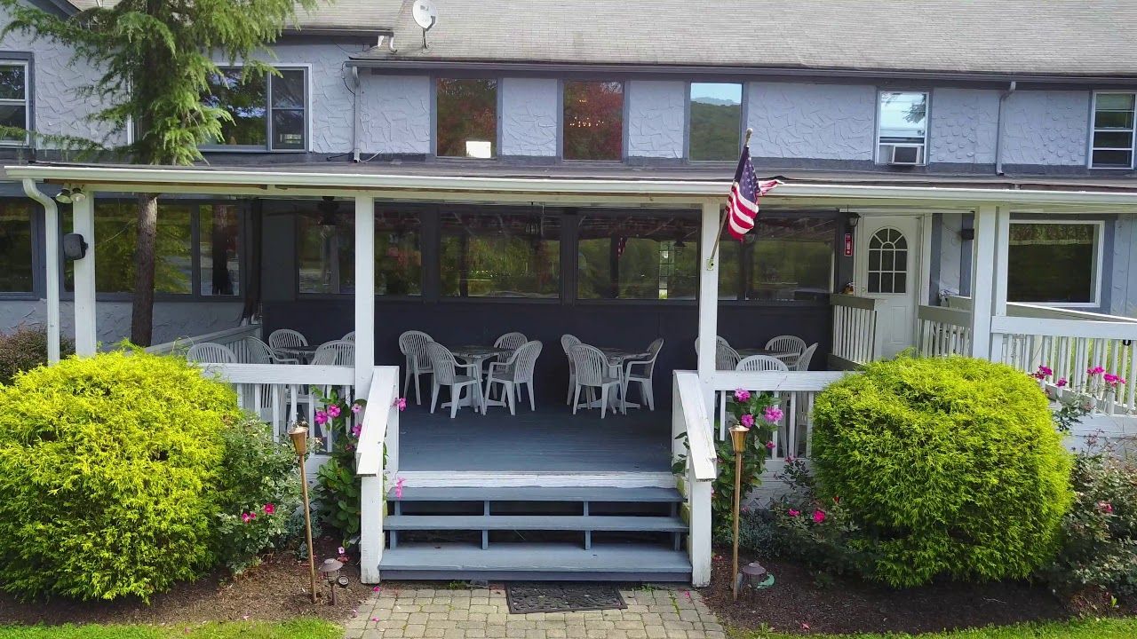 House porch with white chairs, steps, green shrubs, and an American flag