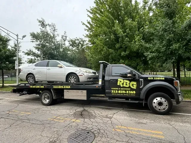 Silver car being towed by a black tow truck with