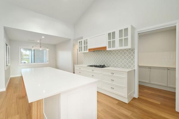 An Empty Kitchen with White Cabinets and A Large Island | Mid-North Coast, NSW | BDM Constructions