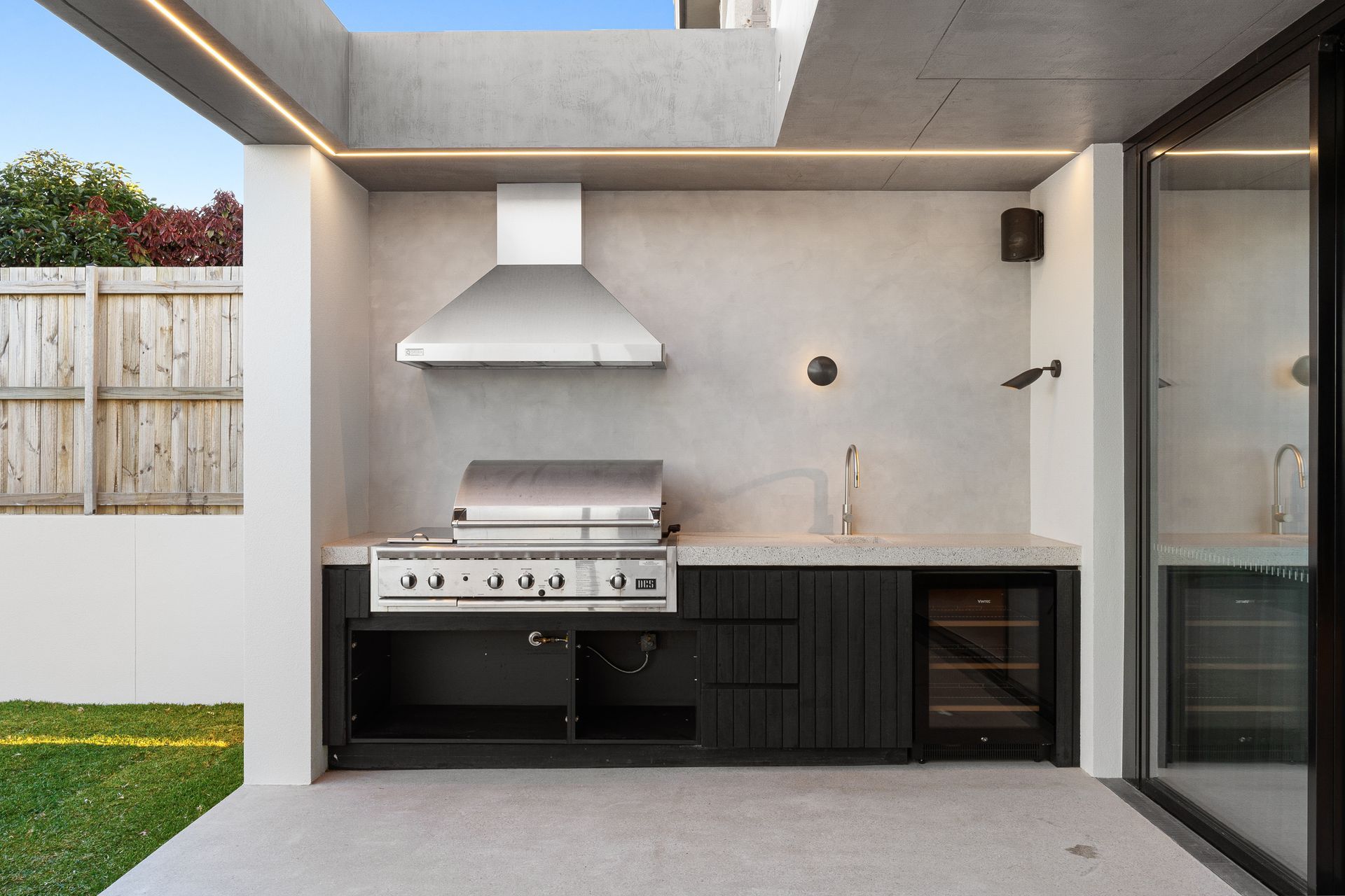 An outdoor kitchen with a grill and a wine cooler