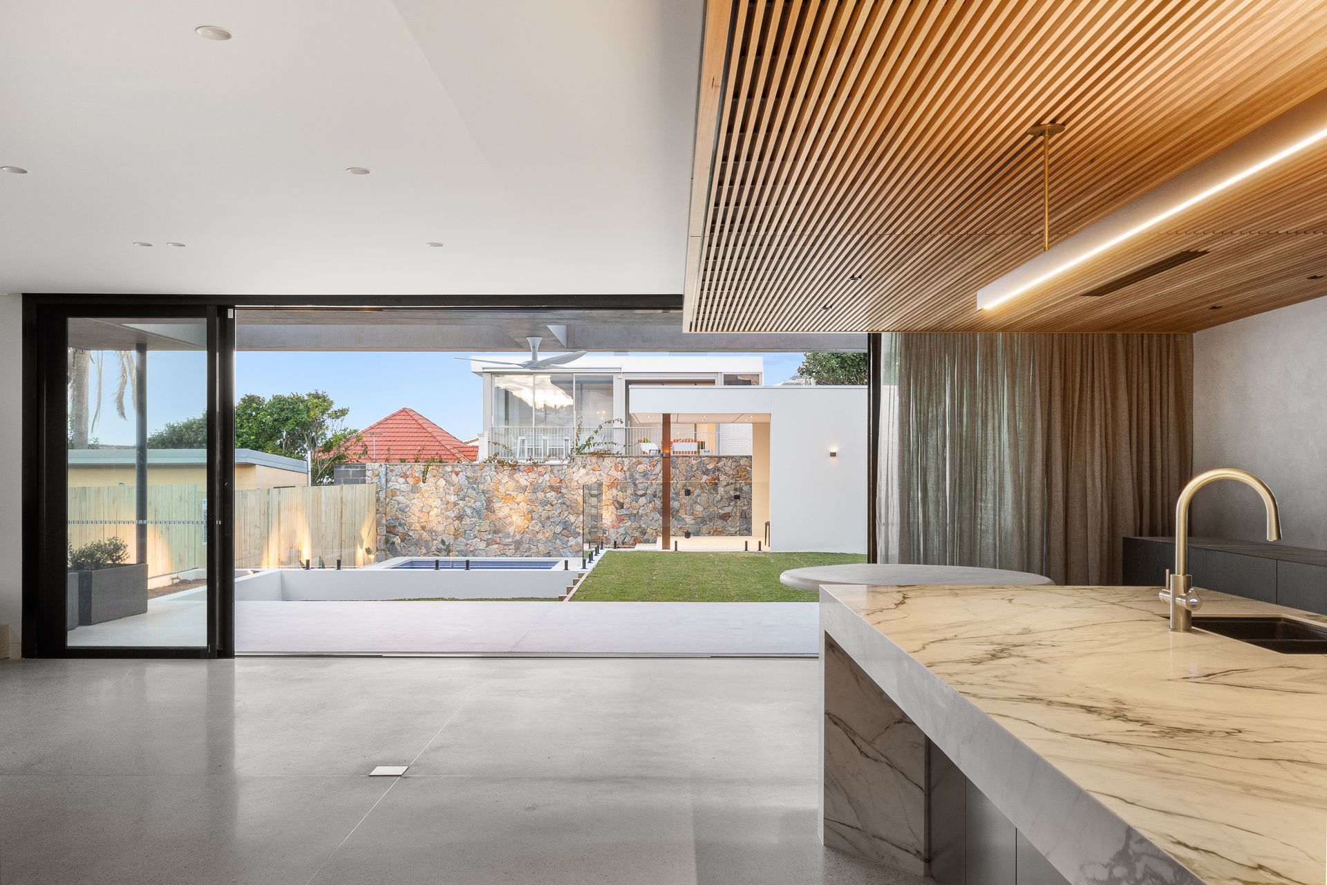 A kitchen with a sink and a sliding glass door leading to a pool.