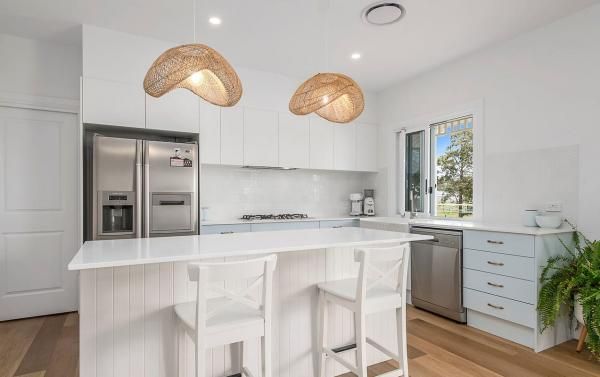 A Kitchen with White Cabinets, Stools, a Refrigerator, and A Window | Mid-North Coast, NSW | BDM Constructions