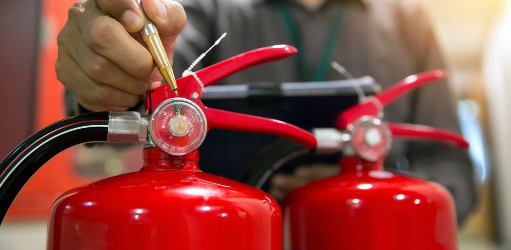 Persona inspeccionando un extintor rojo