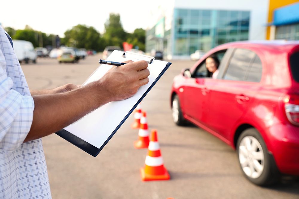 Instructor de manejo con portapapeles observando a una persona que conduce un automóvil rojo 