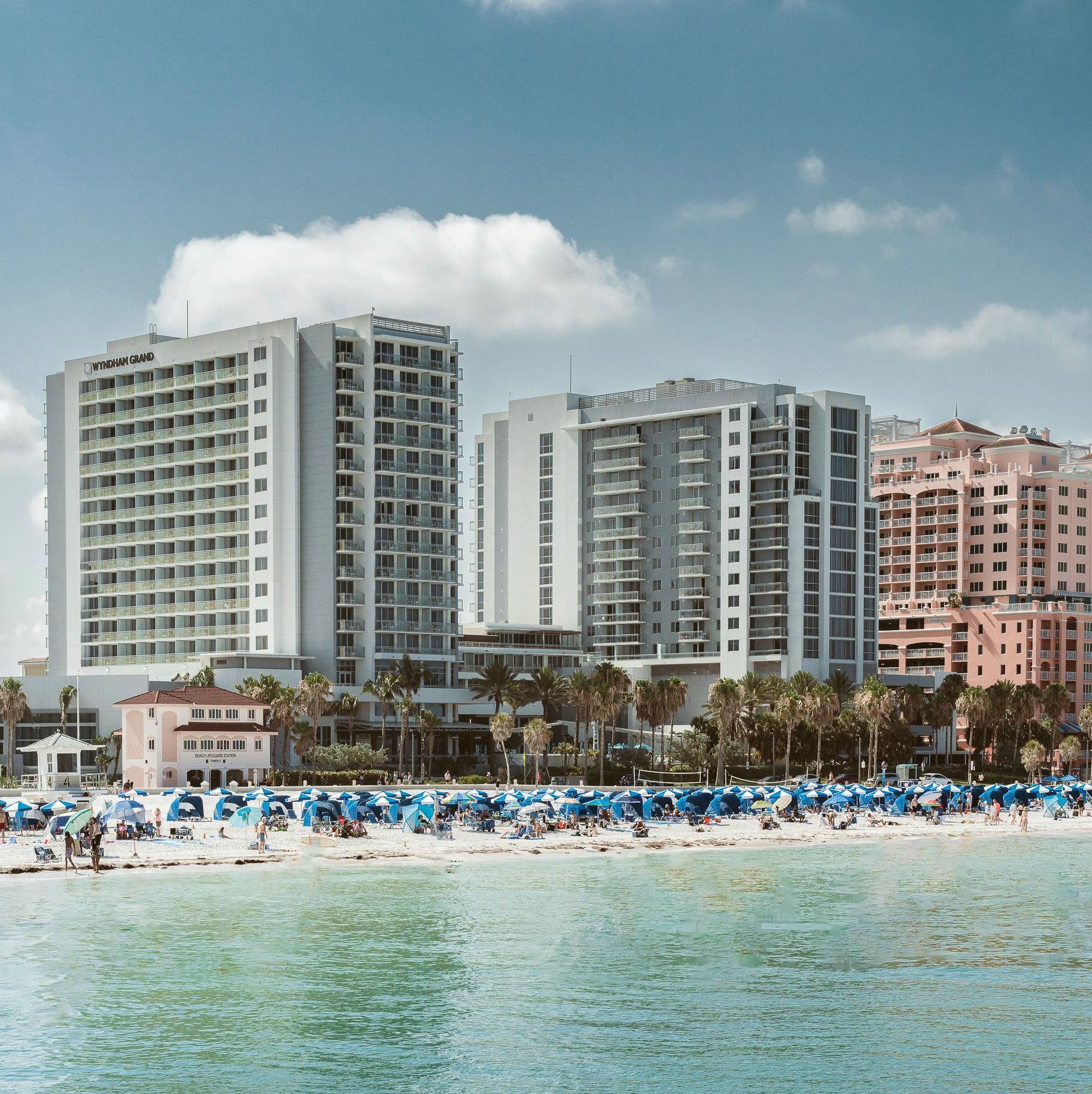 A beach with a lot of umbrellas and buildings in the background