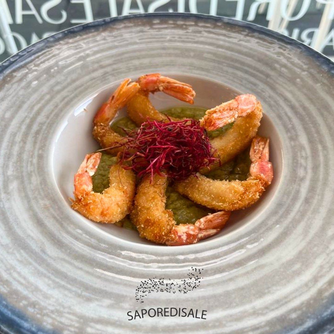 Gamberi fritti con salsa verde, guarnito con microgreens rossi in una ciotola.