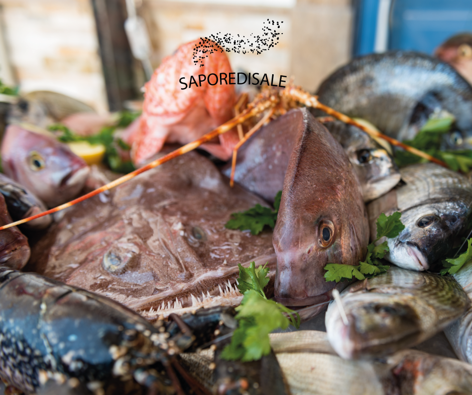 Assortimento di pesce fresco esposto al mercato, tra cui vari tipi di pesce, aragoste e vongole.
