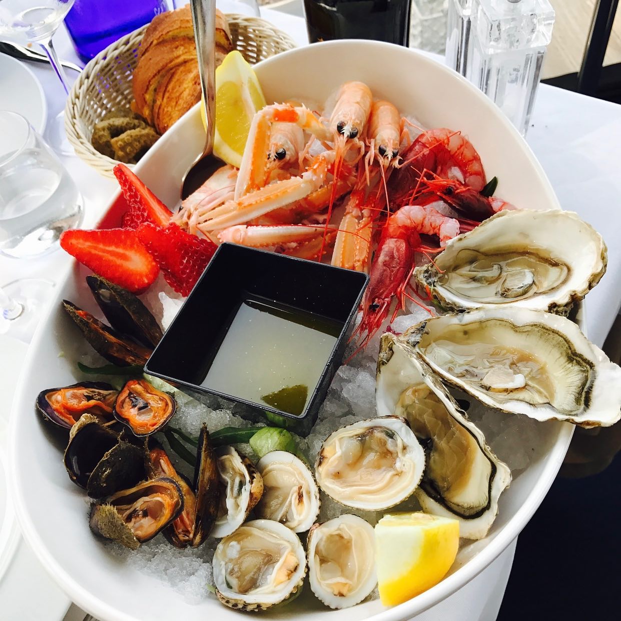 Piatto di frutti di mare con gamberi, ostriche, cozze, vongole, fragole, limone e salsa.