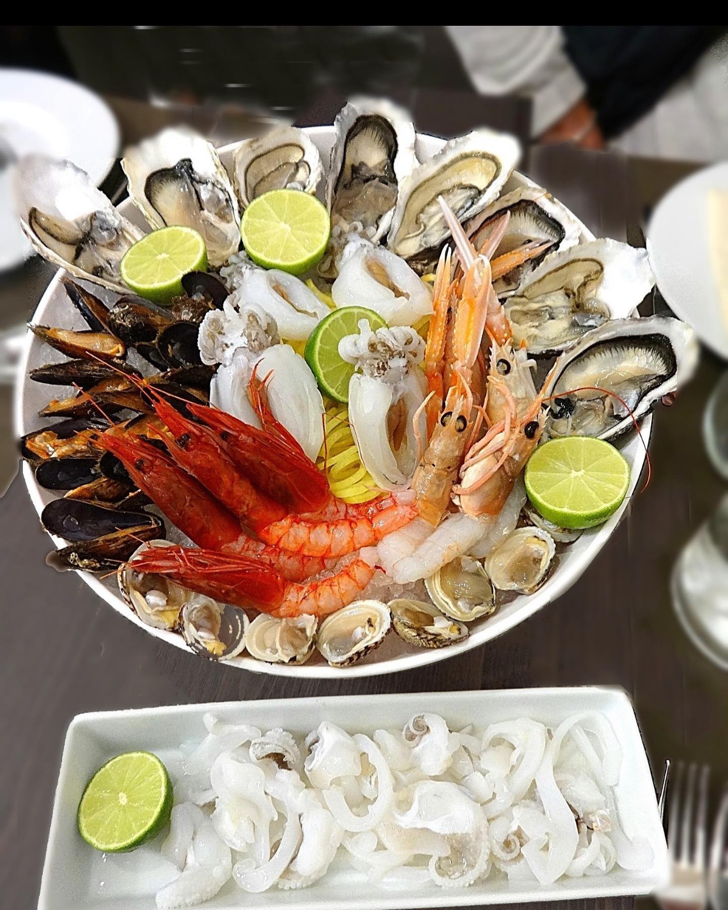 Piatto di frutti di mare con ostriche, cozze, gamberi e calamari, guarnito con lime.