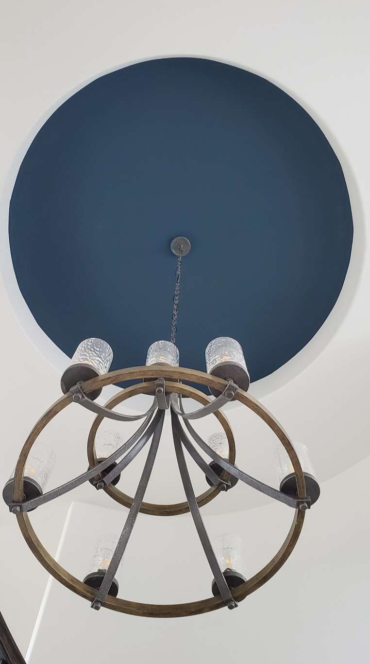 A chandelier is hanging from the ceiling in a room with a blue ceiling.
