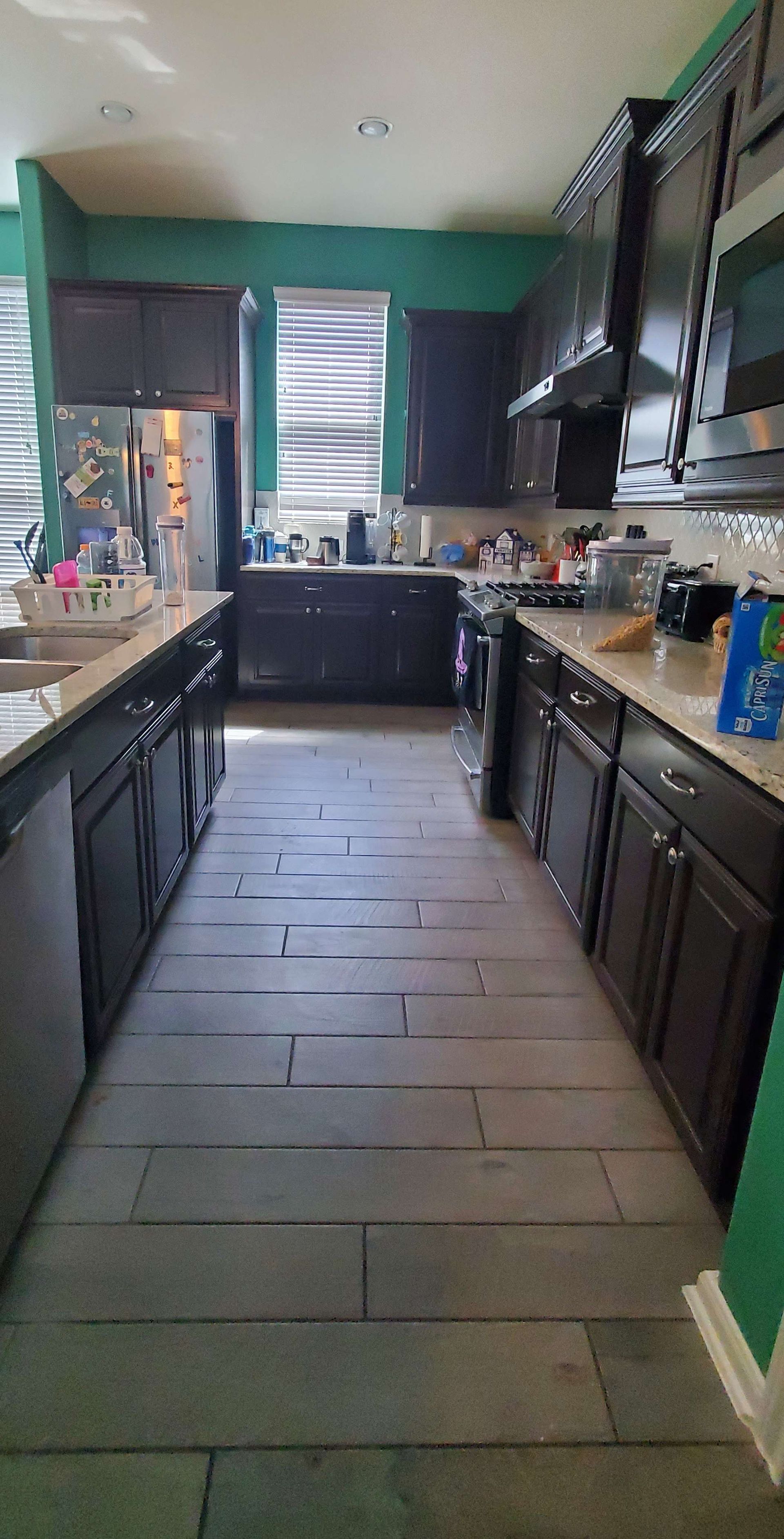 A kitchen with a lot of cabinets and appliances and a tiled floor.