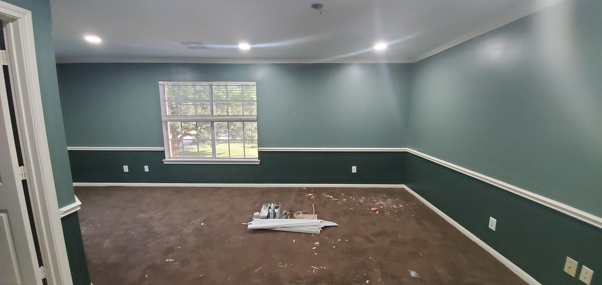 An empty room with green walls and a window.