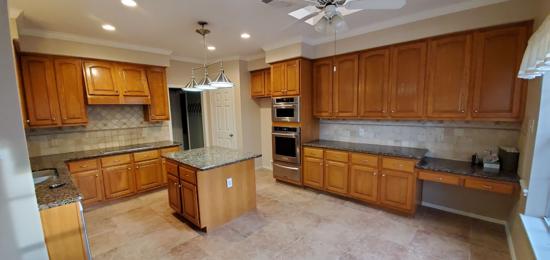 A kitchen with wooden cabinets , granite counter tops , and stainless steel appliances.