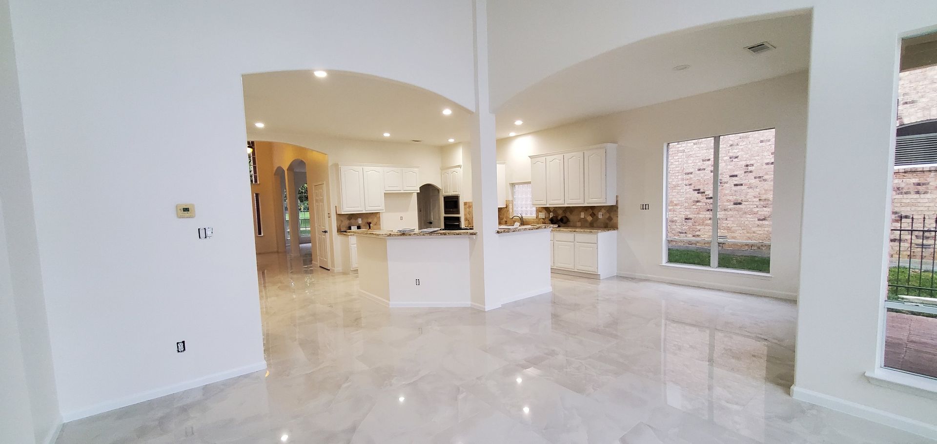 A large empty room with white walls and marble floors in a house.
