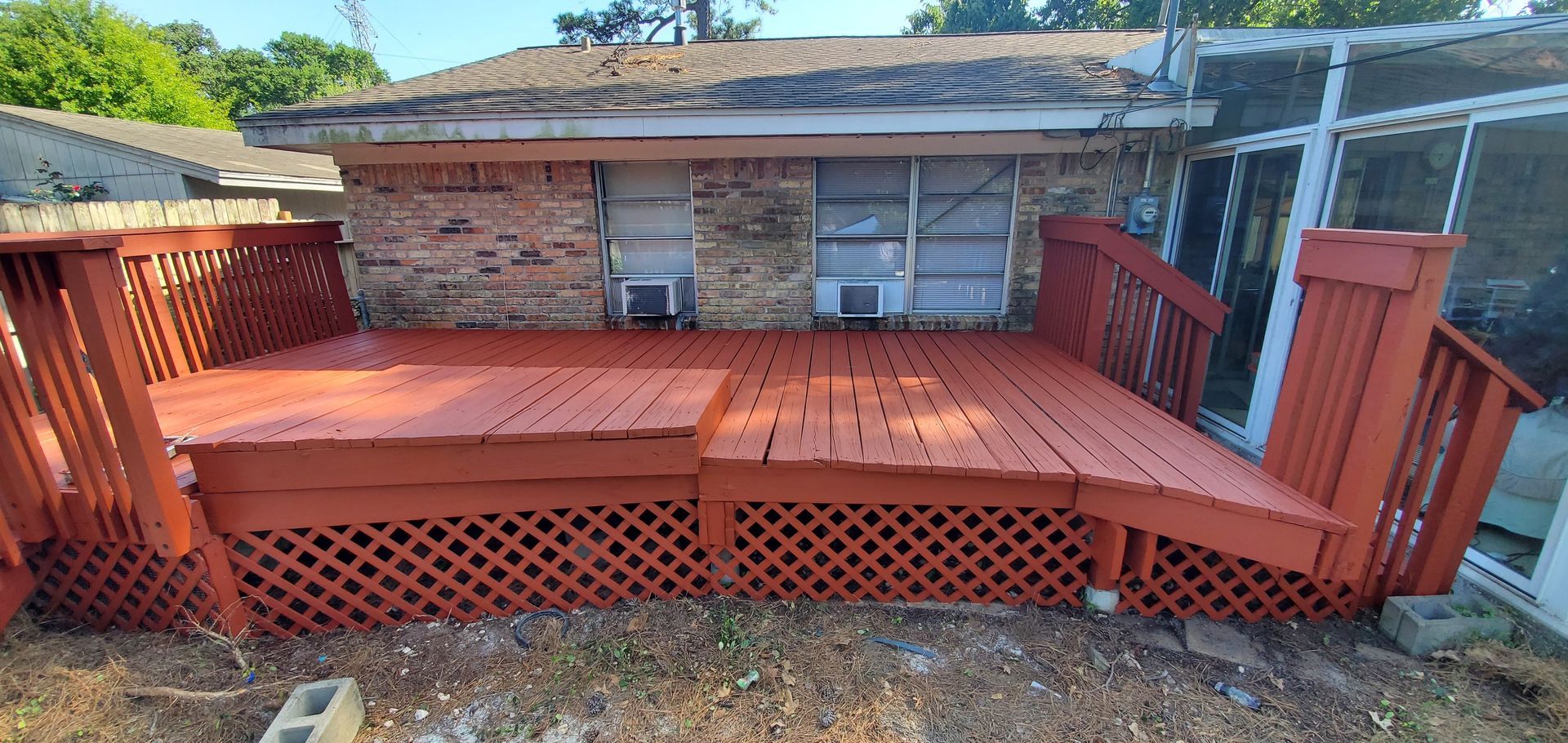 A wooden deck is sitting in front of a brick house.