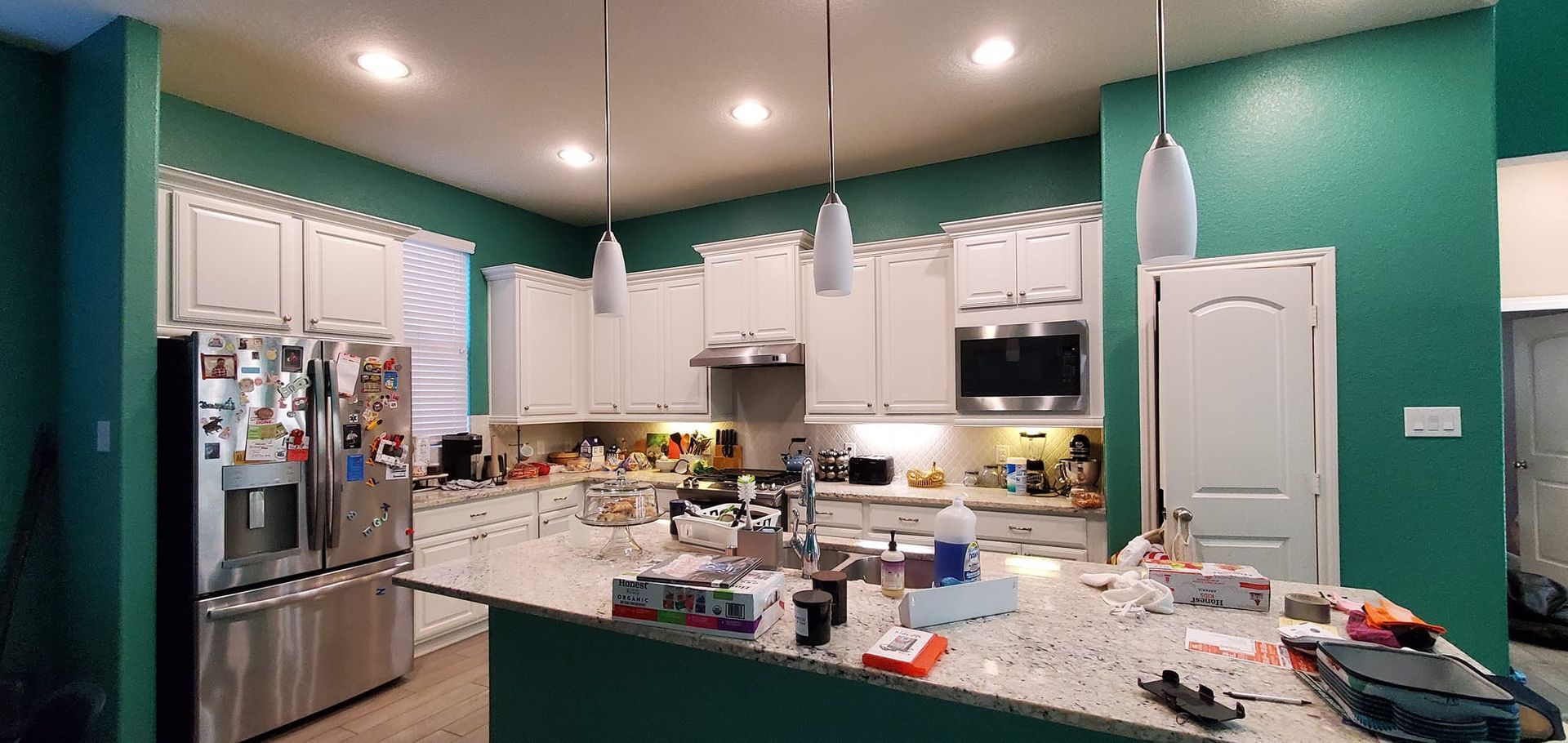 A kitchen with white cabinets and green walls is being remodeled.