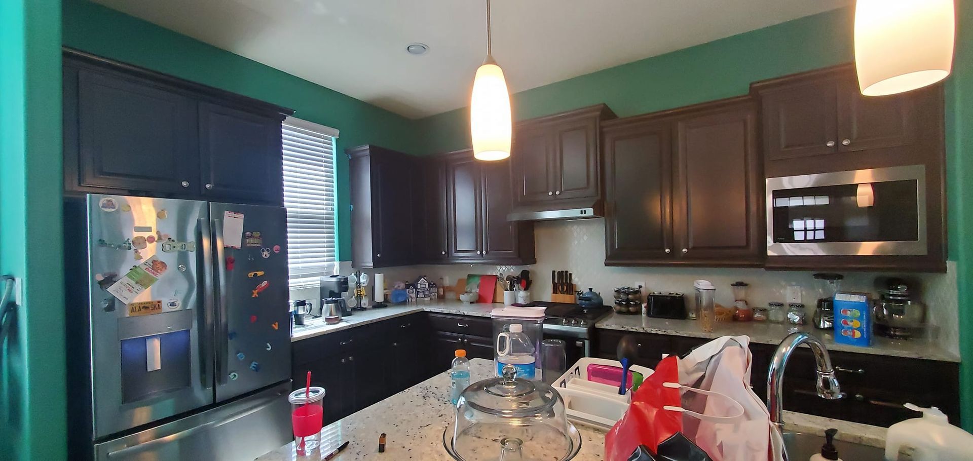 A kitchen with green walls and stainless steel appliances.