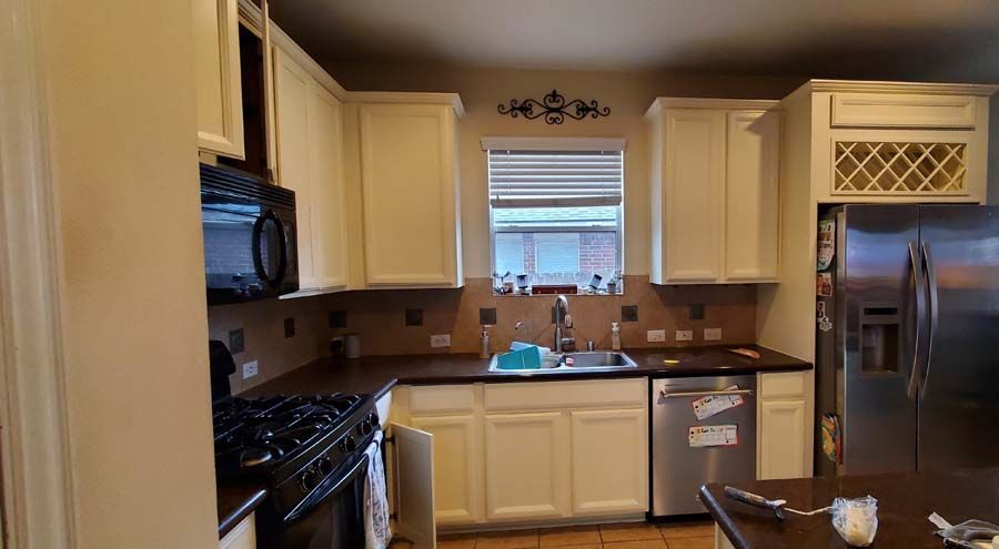 A kitchen with white cabinets , granite counter tops , stainless steel appliances , and a stool.