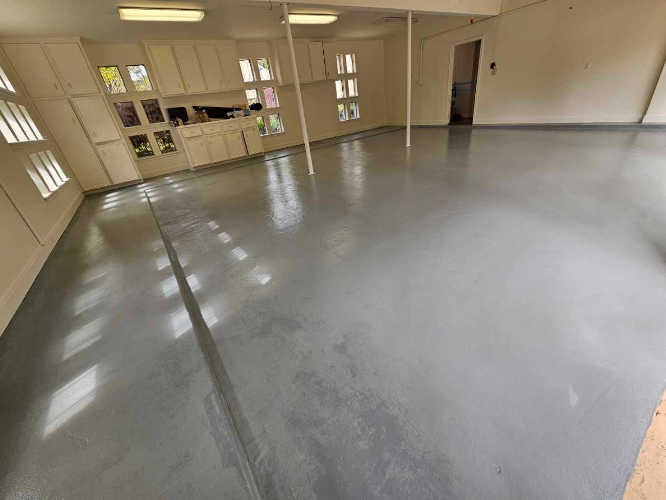 A large empty room with a gray floor and white cabinets.