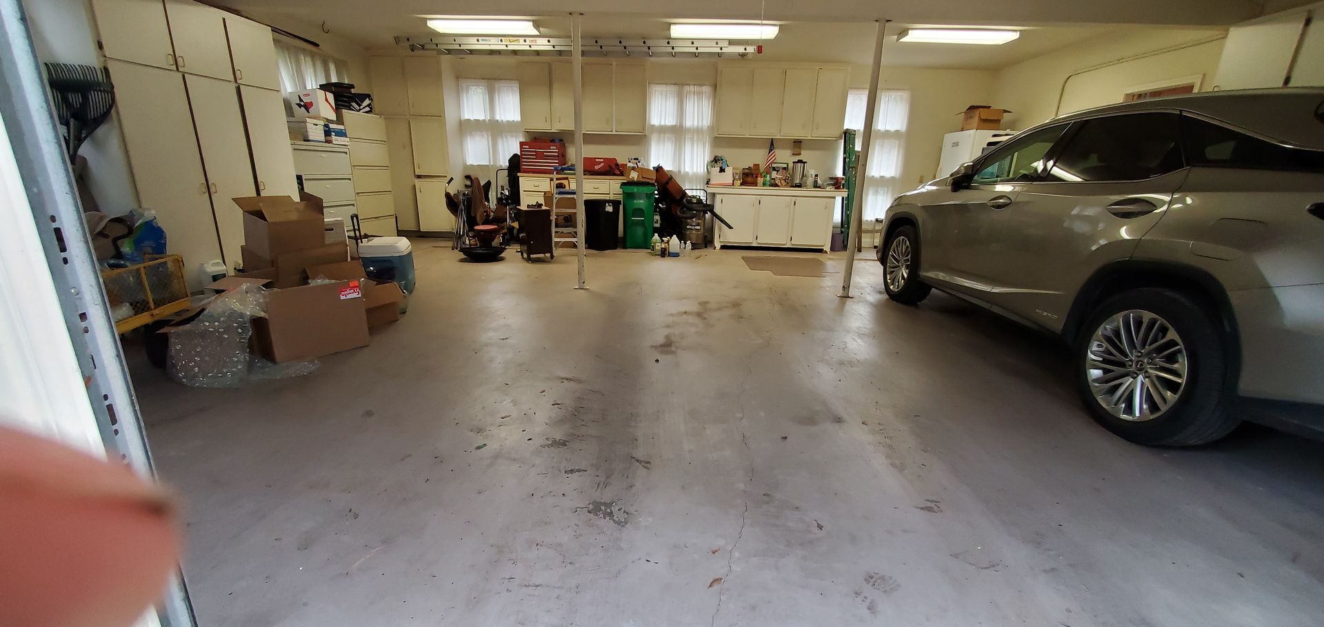 A car is parked in a garage next to a kitchen.