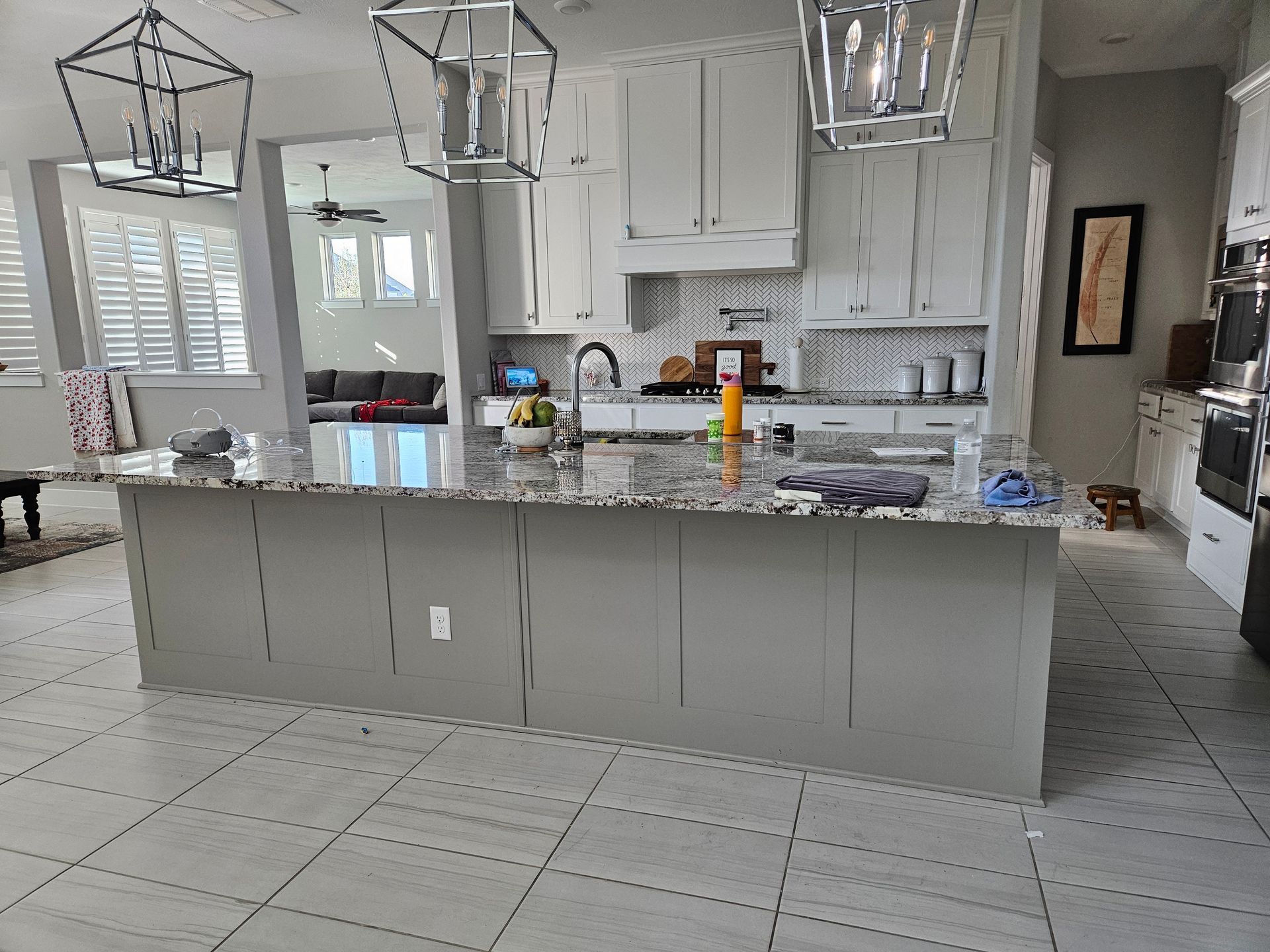 Gray kitchen island with gray cabinets, countertops, and three hanging lights.