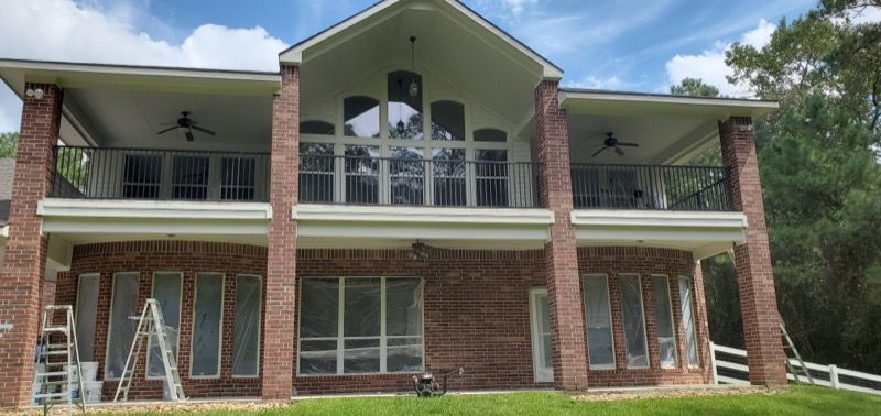 A large brick house with a balcony and a ladder in front of it.