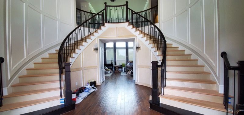 A large curved staircase in a house with a black railing.