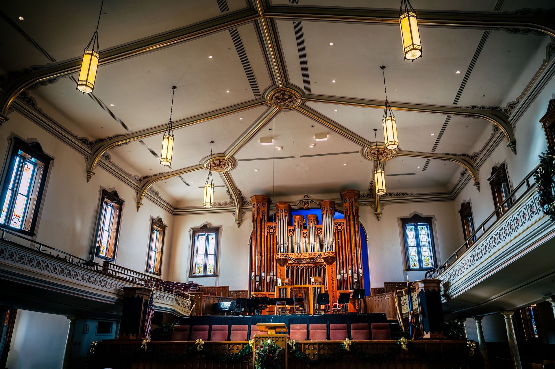 Ornate church interior with a large pipe organ, stained-glass windows, and hanging lights