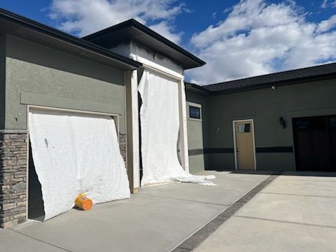 Exterior view of a modern house with a garage and door. White material covers the garage door and frame.