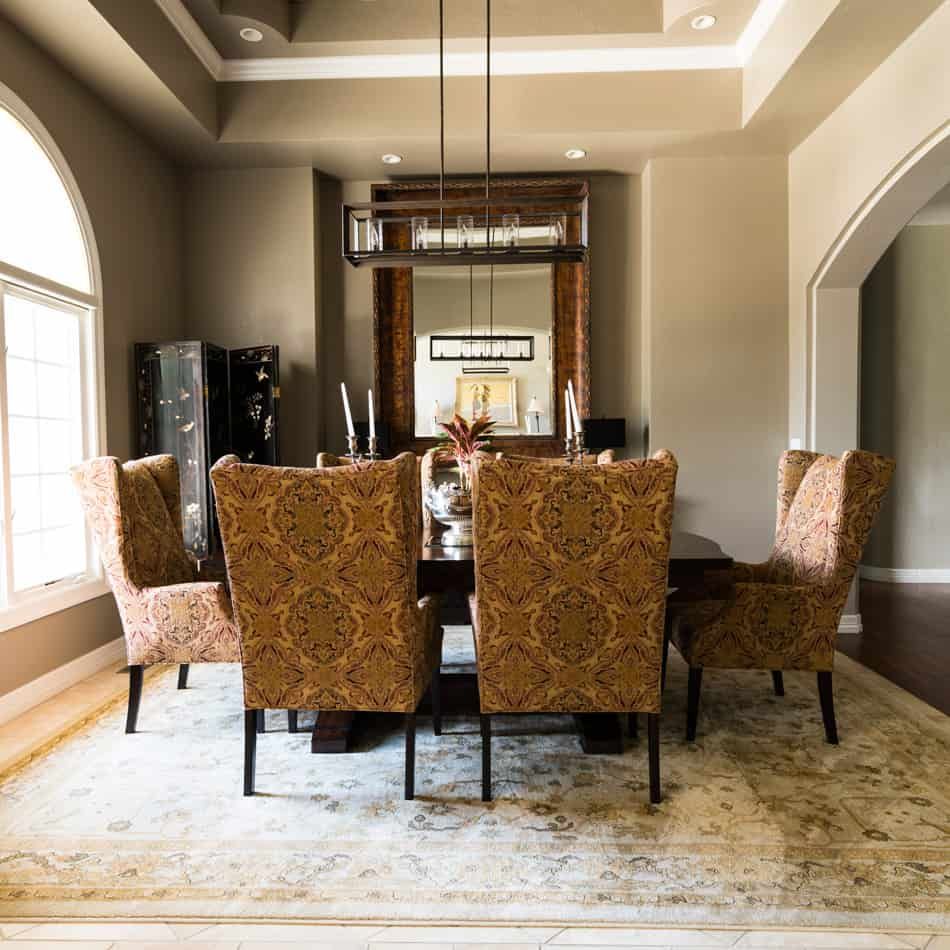 Dining room with table, chairs, and mirror, on an oriental style rug.