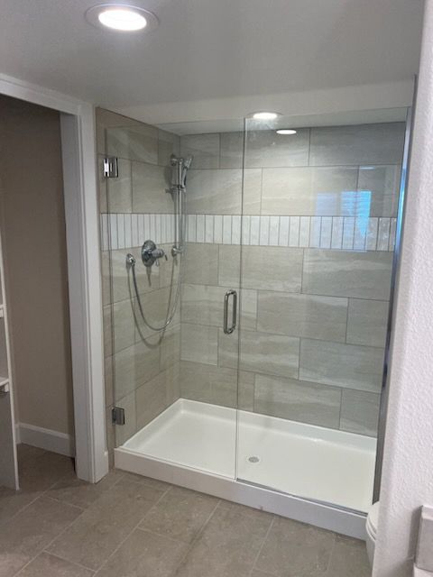 Modern glass shower with tiled walls and a white shower basin.