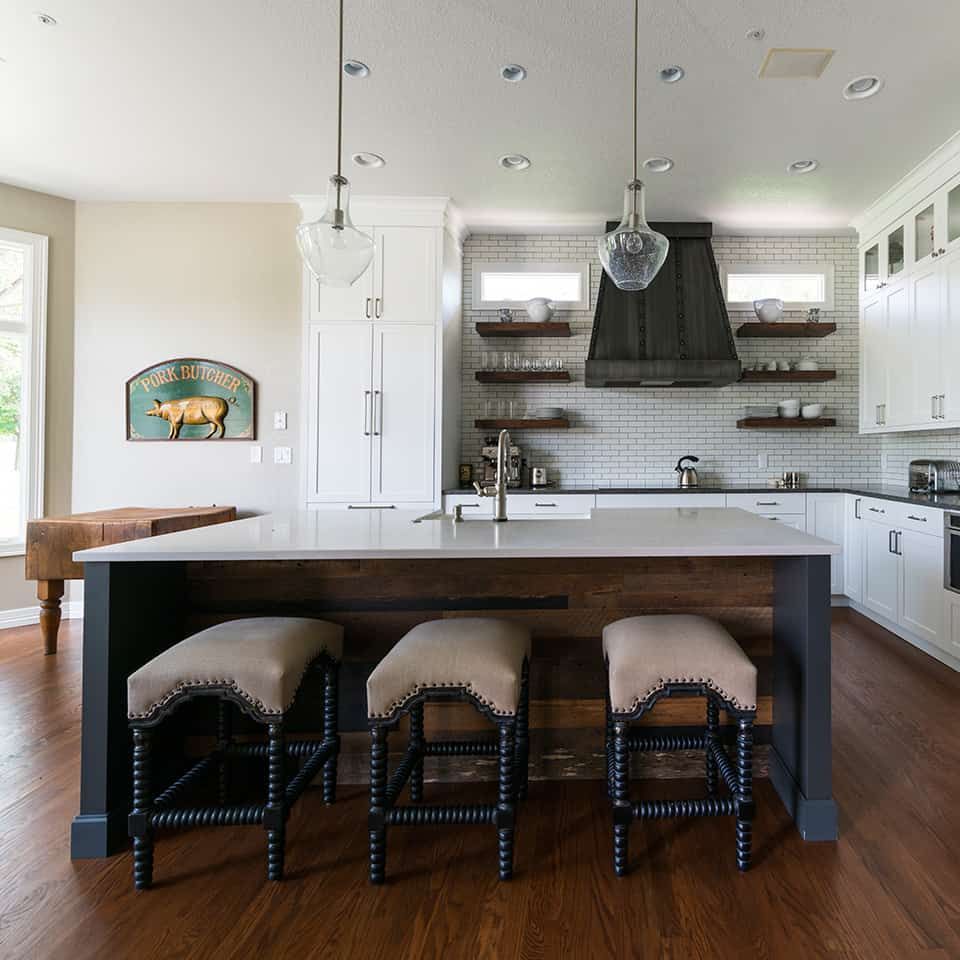 A modern kitchen with a large island, bar stools, and white cabinetry.