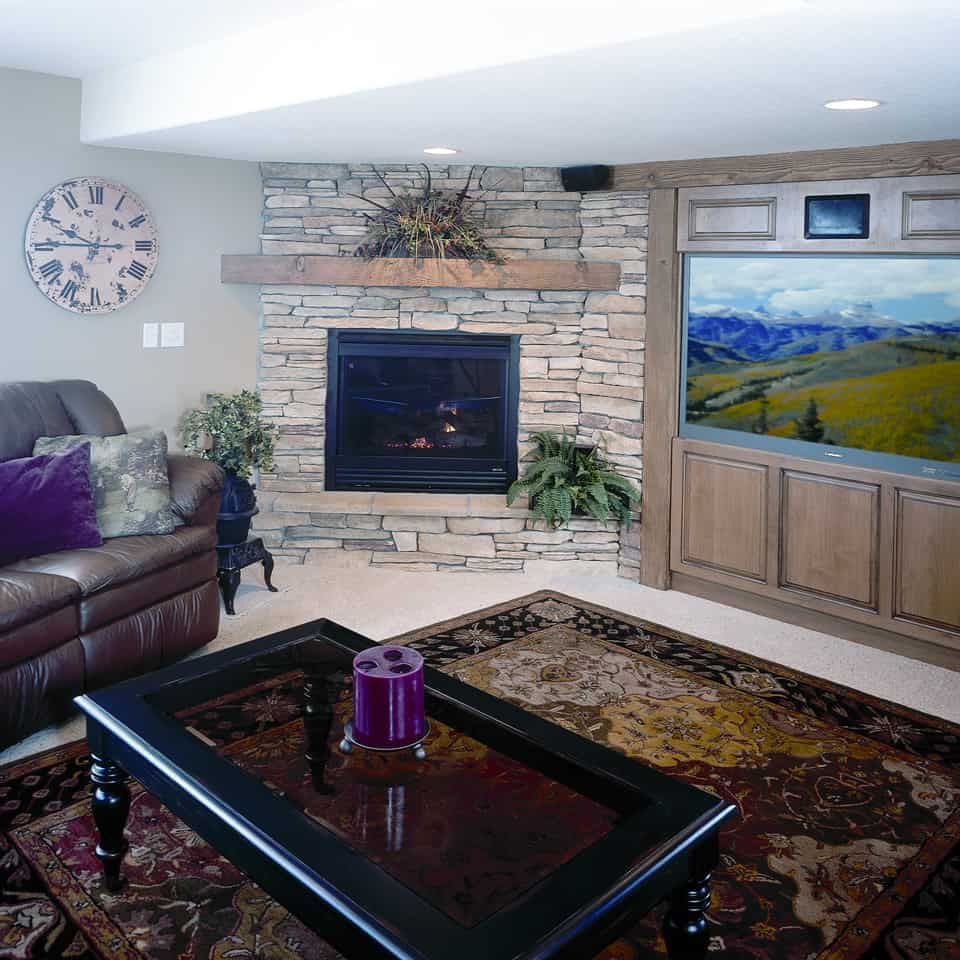 Cozy living room with fireplace, TV, and brown leather couch. Rug and coffee table in the center.